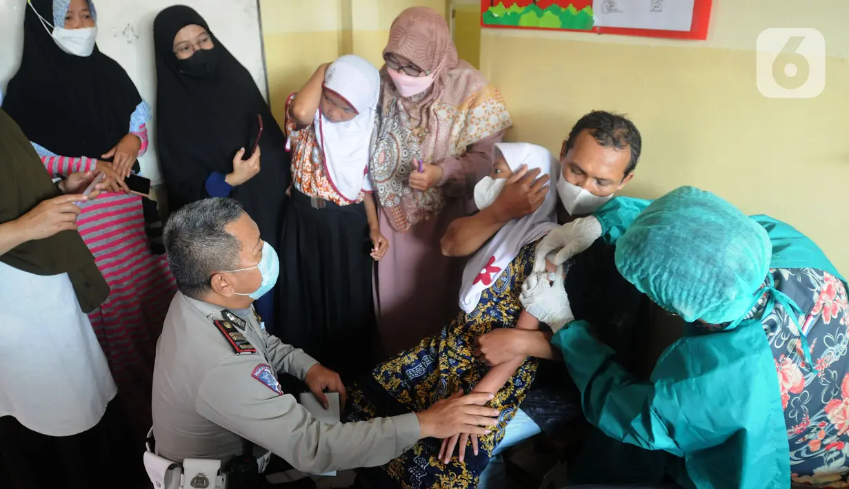Anggota Polri dari Polsek Cinere memegangi murid penyandang tunagrahita saat disuntik vaksin COVID-19 di SLB BC Manunggal Bhakti, Depok, Selasa (11/1/2022). Delapan murid SLB disuntik vaksin COVID-19 Sinovac yang merupakan rangkaian program Vaksinasi Merdeka. (merdeka.com/Arie Basuki)