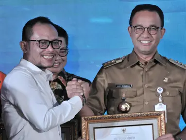 Gubernur DKI Jakarta Anies Baswedan (kanan) menerima penghargaan dari Menteri Ketenagakerjaan Hanif Dhakiri (kiri) dalam Indeks Pembangunan Ketenagakerjaan (INTEGRA) 2018 di Kantor Kemnaker, Jakarta, Senin (19/11). (Merdeka.com/Iqbal Nugroho)