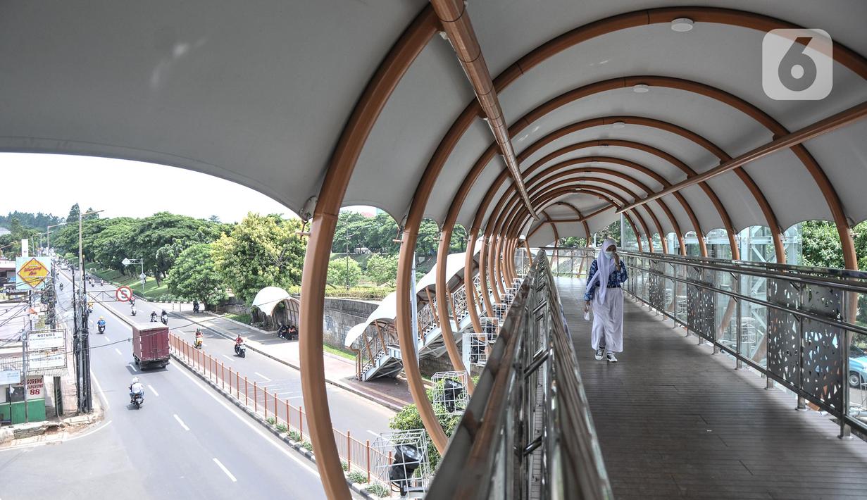 Pejalan kaki menggunakan fasilitas jembatan penyeberangan orang (JPO) di Jalan Kolonel Sugiono, Duren Sawit, Jakarta Timur, Senin (7/2/2022). JPO Kolonel Sugiono yang berada dekat Kanal Banjir Timur itu didesain dengan bentuk yang modern namun sarat kearifan lokal. (merdeka.com/Iqbal S Nugroho)