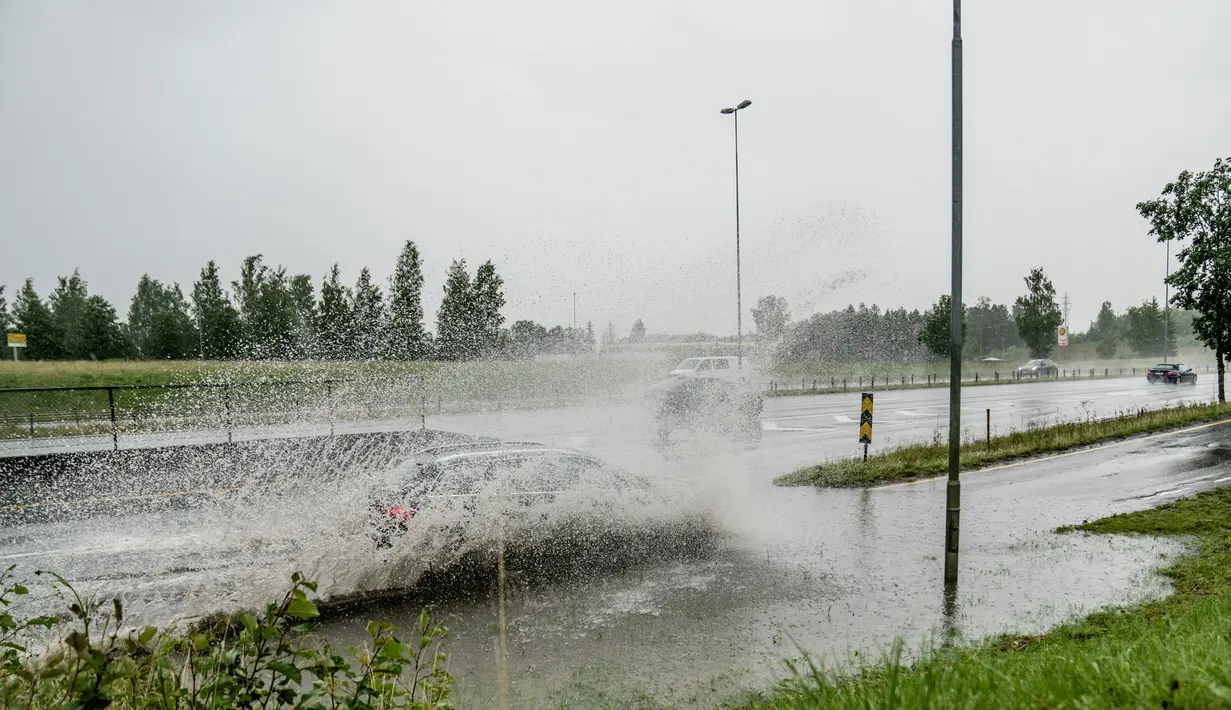 Sebuah mobil melewati banjir saat badai Hans di pintu keluar jalan raya di E6 dekat Klofta, utara Oslo, pada 7 Agustus 2023. (Stian Lysberg Solum / NTB / AFP)