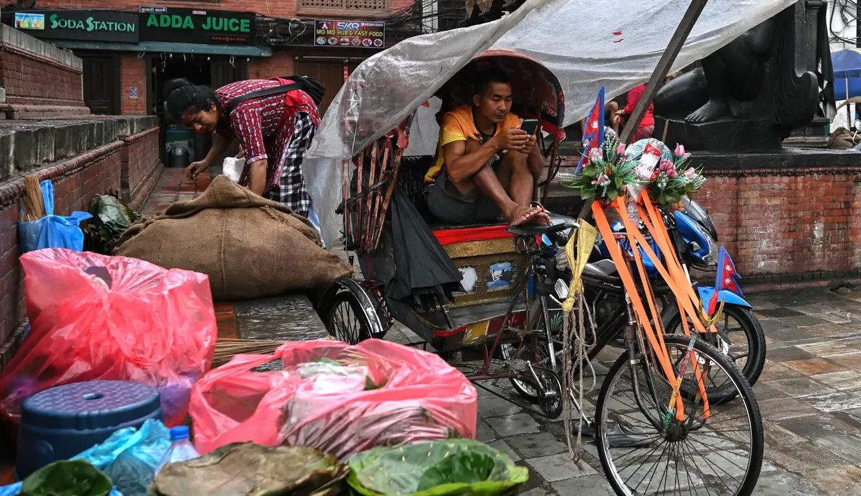 Seorang penarik becak menggunakan telepon seluler di Durbar Square, Kathmandu, Nepal pada 13 September 2025. (Arun SANKAR/AFP)