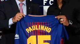 Pemain Baru Barcelona, Paulinho foto bersama dengan Presiden Barcelona Josep Maria Bartomeu saat perkenalan dirinya di Stadion Nou Camp, Barcelona, (17/8). Paulinho akan mengenakan jersey bernomor punggung 15. (AFP Photo/Lluis Gene)