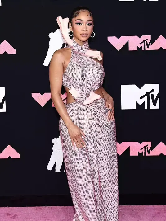 Rapper Saweetie tampil mencuri atensi mengenakan gaun halter warna pink dengan tulang besar yang menempel di bagian atas gaunnya.  [@upscalemagazine]
