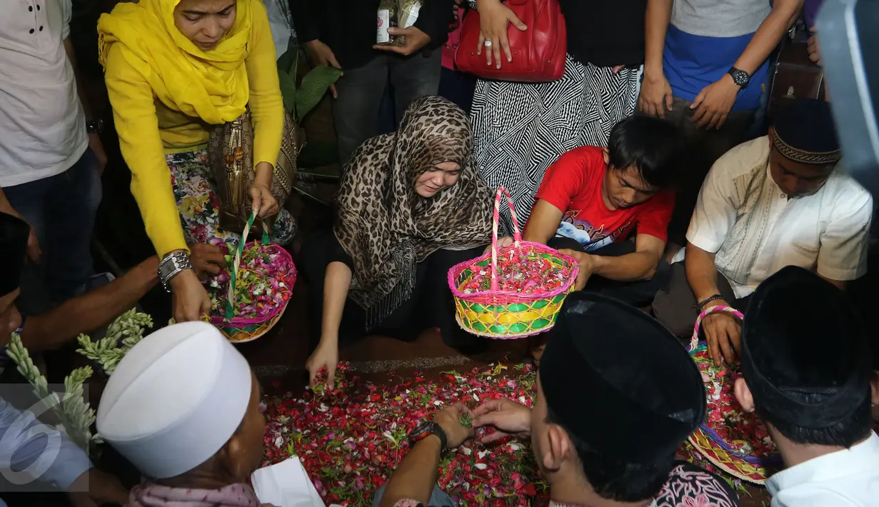 Istri Budi Anduk, Neneng Nurhayati menaburkan bunga di makam Budi Anduk, Bekasi, Senin (11/1/2016). Budi Anduk menghembuskan nafas terakhir pada usia 47 tahun di RS Dharmais, Jakarta. (Liputan6.com/Herman Zakharia)