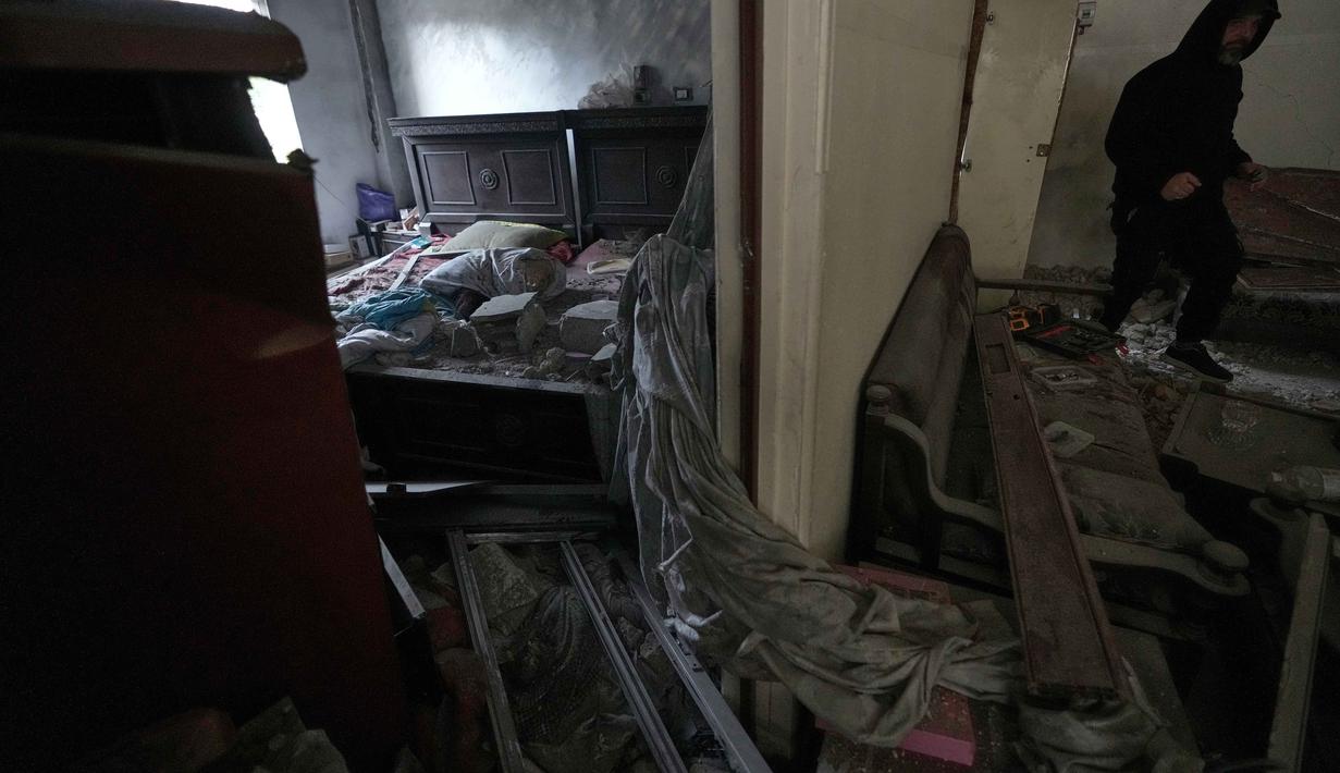 Pada Minggu (22/3/2025), serangan udara Israel menghancurkan infrastruktur strategis, termasuk Jembatan Qasmiyeh di atas Sungai Litani yang merupakan jalur penghubung penting. Tampak dalam foto, seorang pria memeriksa apartemennya di lokasi bangunan yang hancur akibat serangan udara Israel di kota pelabuhan Tyre, Lebanon selatan, Kamis, 26 Maret 2026. (AP Photo/Hussein Malla)