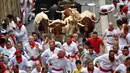 Peserta bersuka ria berlari di samping banteng selama Festival San Fermin di Pamplona, Spanyol, Senin (9/7). Festival berbahaya ini diikuti oleh peserta dari seluruh penjuru dunia. (AP Photo/Alvaro Barrientos)