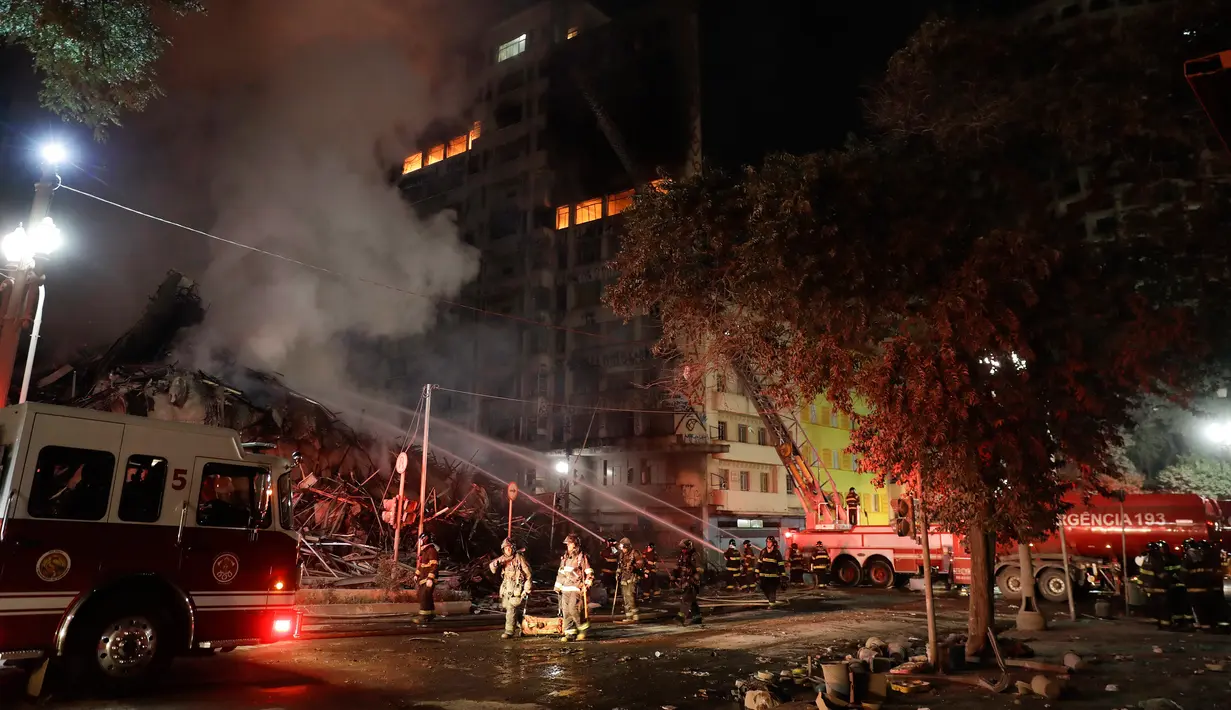 Petugas pemadam kebakaran berusaha memadamkan api yang melahap bangunan 26 lantai di Sao Paulo, Brasil, Selasa (1/5). Saksi mengatakan api menyebar dengan cepat dari salah satu lantai bawah dan membakar bangunan yang bersebelahan. (AP/Andre Penner)