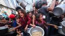 Sedikitnya, 650.000 anak menghadapi kelaparan akut dan 22.000 pasien yang membutuhkan perawatan terjebak di Gaza akibat kekurangan pasokan obat-obatan, bahan bakar, dan makanan. Tampak dalam foto, anak-anak Palestina berdesak-desakan untuk mendapatkan makanan hangat dari dapur amal di kamp pengungsi Nuseirat di Jalur Gaza yang dikepung Israel pada 4 September 2025. (Eyad BABA/AFP)