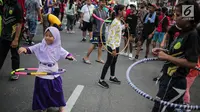 Anak-anak bermain permainan tradisional hula hoop ditemani sejumlah mahasiswa dari Penggerak Olahraga saat car free day (CFD) di kawasan Bundaran HI, Jakarta, Minggu (14/7/2019). Kegiatan yang rutin digelar ini bertujuan mengajak masyarakat DKI Jakarta aktif berolahraga. (Liputan6.com/Faizal Fanani)