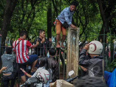 Sejumlah warga memanjat pagar untuk menyaksikan Konser Drug Free Asia Africa di kawasan Monas, Jakarta, Minggu (19/4/2015). Aksi nekat warga ini ditengarai oleh petugas yang menutup akses masuk pengunjung Monas. (Liputan6.com/Faizal Fanani)