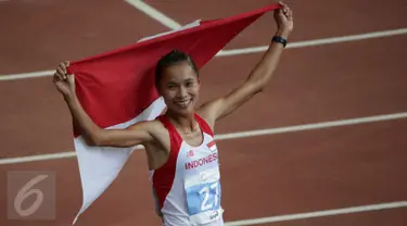 Atlet Indonesia, Rini Budiarti membentangkan bendera Merah Putih usai finish pertama lari halang rintang 3.000 meter SEA Games ke-28 di National Stadium, Singapura, (12/6/2015). Rini mencatat waktu 10 menit 20,40 detik. (Liputan6.com/Helmi Fithriansyah)