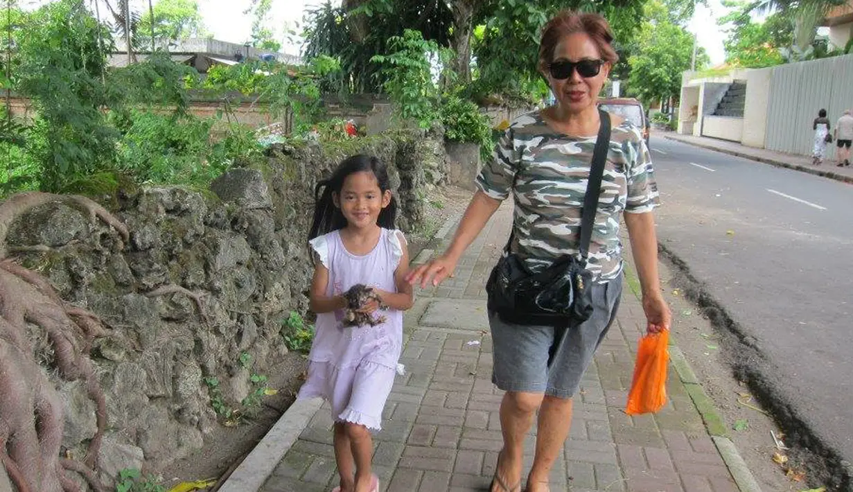 Angeline bersama dengan ibu angkatnya Margriet sedang berjalan kaki di Bali. Angeline terlihat sedang membawa anak kucing. Foto ini diberi keterangan bahwa Angeline menemukan anak kucing yang terlantar. (Facebook.com/Find Angeline - Bali's Missing Child)