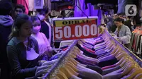 Para calon pembeli memilih pakaian impor bekas di Pasar Senen, Jakarta, Kamis (9/3/2023). Menteri Perdagangan Zulkifli Hasan mengatakan pemerintah tidak melarang bisnis baju bekas, tetapi impor baju bekas yang jadi produk bisnis thrifting jelas dilarang. (Liputan6.com/Faizal Fanani)