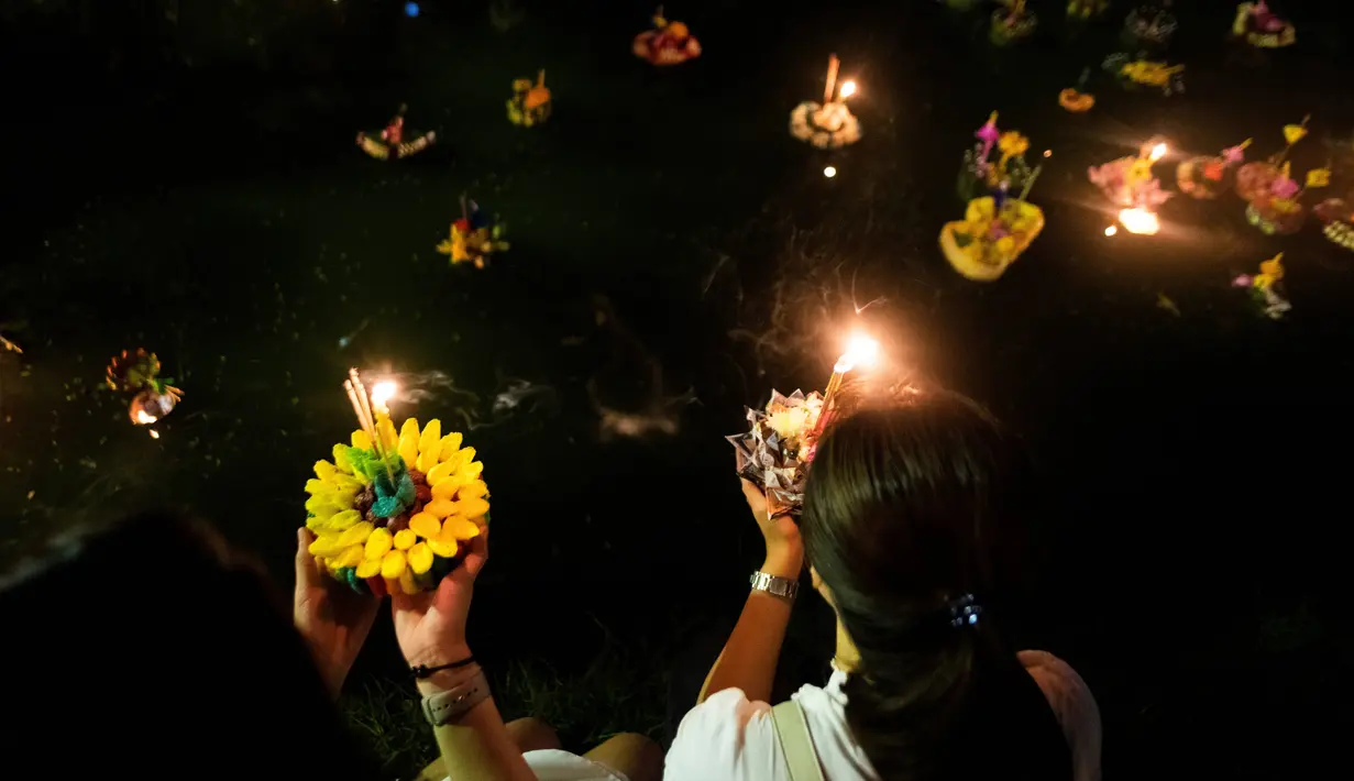 Dua wanita Thailand bersiap menghayutkan 'krathong' untuk merayakan festival Loy Krathong di sebuah danau di Bangkok, Kamis (22/11). Loy Krathong adalah ritual melarung wadah berbentuk lotus yang didalamnya diberi sesajen, lilin dan dupa (Jewel SAMAD/AFP)