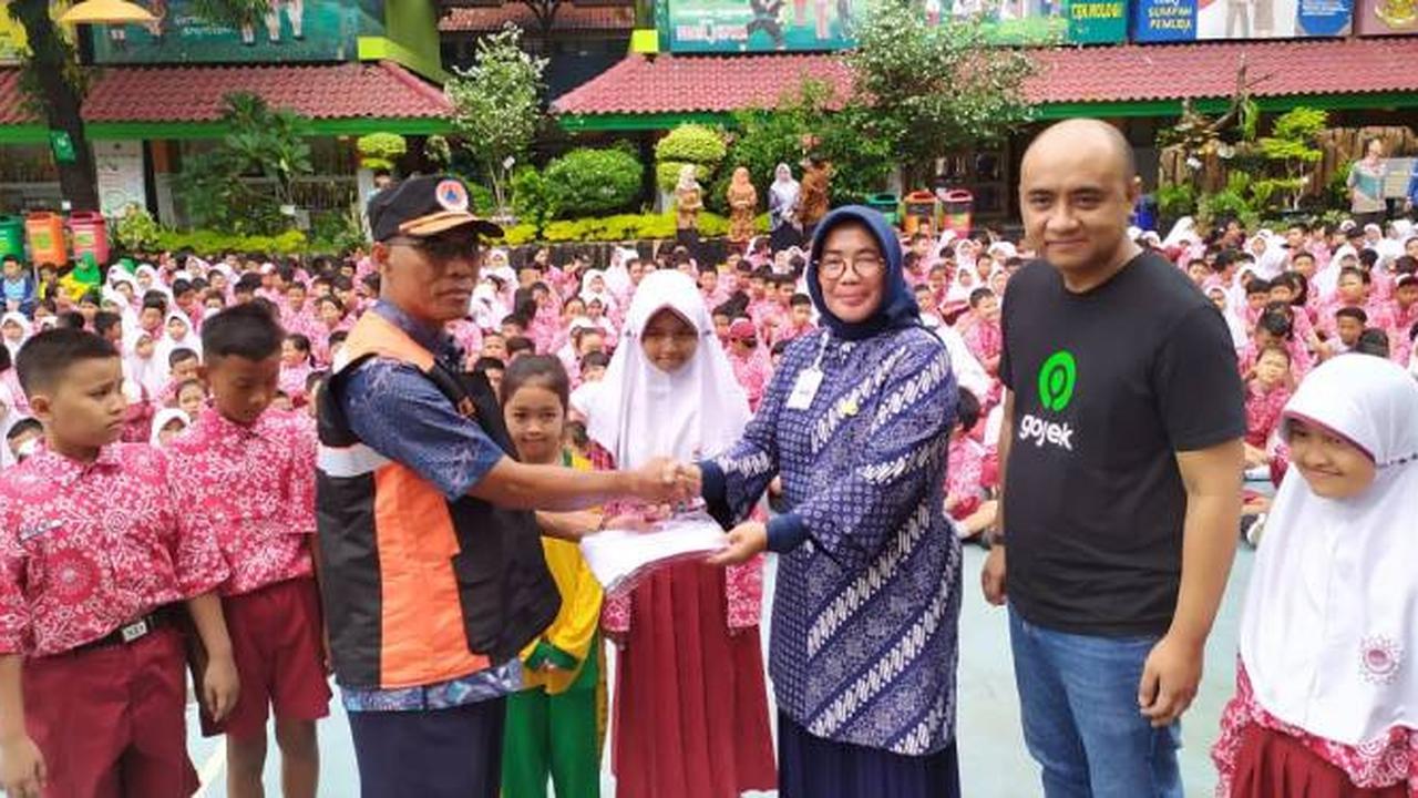 Kepala BPBD DKI Jakarta Subejo secara simbolis memberikan bantuan seragam sekolah dari Gojek kepada Kepala SDN Kapuk Muara 03 Melfa Christine, didampingi SVP Public Policy and Government Relations Gojek Panji Ruky di Penjaringan, Jakarta Utara. Dok: Gojek