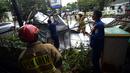 Petugas pemadam kebakaran memotong rangka reklame di Jalan Soepomo, Jakarta, Sabtu (28/5/2022). Hujan disertai angin kencang pada pagi tadi membuat papan reklame roboh sehingga membuat kemacetan arus lalu lintas di jalan tersebut. (merdeka.com/Imam Buhori)