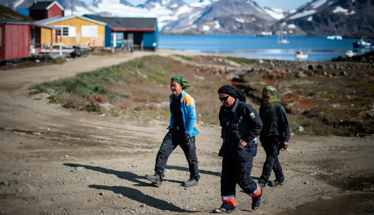 Warga berjalan di Desa Kulusuk, Kota Sermersooq, Greenland, Denmark, 16 Agustus 2019. Kawasan Greenland membeku sepanjang tahun termasuk di musim panas. (Jonathan NACKSTRAND/AFP)