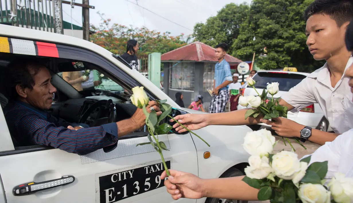 Umat Buddha Myanmar memberikan mawar putih kepada umat Islam yang akan melaksanakan salat Id pada perayaaan Idul Fitri di kota Than Lyin, Yangon, Rabu (5/6/2019). Tindakan itu dilakukan beberapa minggu setelah kelompok garis keras berusaha menghapuskan doa selama bulan Ramadhan. (Sai Aung MAIN/AFP)