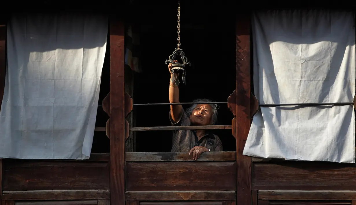 Seorang warga menyalakan lampu untuk menyambut ritual Seto Machindranath di Kathmandu, Nepal (4/4). Dalam ritual ini mereka berdoa meminta hujan serta panen yang melimpah. (AP Photo / Niranjan Shrestha)