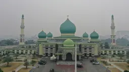 Gambar udara menunjukkan sebuah masjid ketika kabut asap pekat menyelimuti Pekanbaru, Riau, Minggu (15/9/2019). Menurut Data AirVisual, hingga pagi tadi kualitas udara Riau menunjukkan indeks tidak sehat dengan parameter Air Quality Index (AQI) atau indeks kualitas udara 161. (ADEK BERRY/AFP)