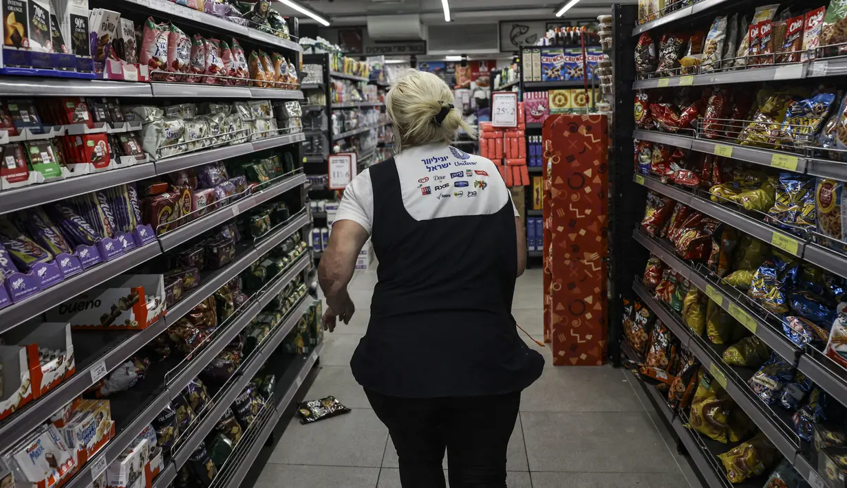 Seorang perempuan berlari menyelamatkan diri setelah mendengar sirene yang memperingatkan adanya tembakan di sebuah supermarket di kota Ashkelon, Israel selatan, pada 11 Oktober 2023. (Photo by RONALDO SCHEMIDT / AFP)