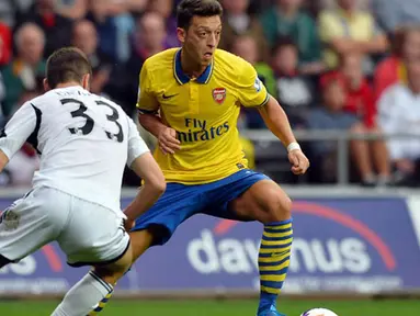 Pemain Arsenal Mesut Ozil dihadang Pemain Swansea City Ben Davies Pada pertandingan Liga Premier Inggris antara Swansea City dan Arsenal di Stadion Liberty di Swansea (28/09/13). (AFP/Paul Ellis)