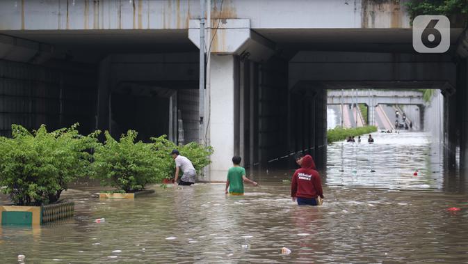 Warga melintasi banjir di terowongan Jalan Angkasa, Jakarta, Selasa (25/2/2020). Hujan yang mengguyur Jakarta sejak Senin (24/2) malam membuat sejumlah kali meluap dan menyebabkan banjir di terowongan tersebut. (Liputan6.com/Helmi Fithriansyah)