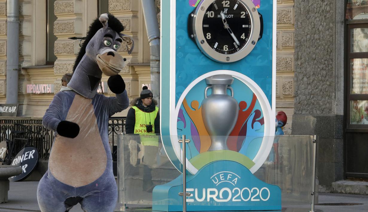 Seorang penampil berkostum kuda berjalan dekat layar hitung mundur Piala Eropa 2020 di St. Petersburg, Rusia, Selasa (17/3/2020). UEFA resmi menunda Piala Eropa 2020 hingga tahun depan. (AP Photo/Dmitri Lovetsky)