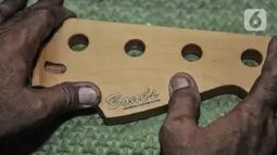 Bone saat menempelkan label pada salah satu gitar buatannya di workshop Bone's Costum Guitar, Jatinegara, Jakarta, Rabu (10/3/2021). Sementara untuk pembuatan gitar atau bass costum, Bone membanderol Rp1,5 juta sampai Rp6 juta per buah, tergantung jenis bahan dan model. (merdeka.com/Iqbal S Nugroho)