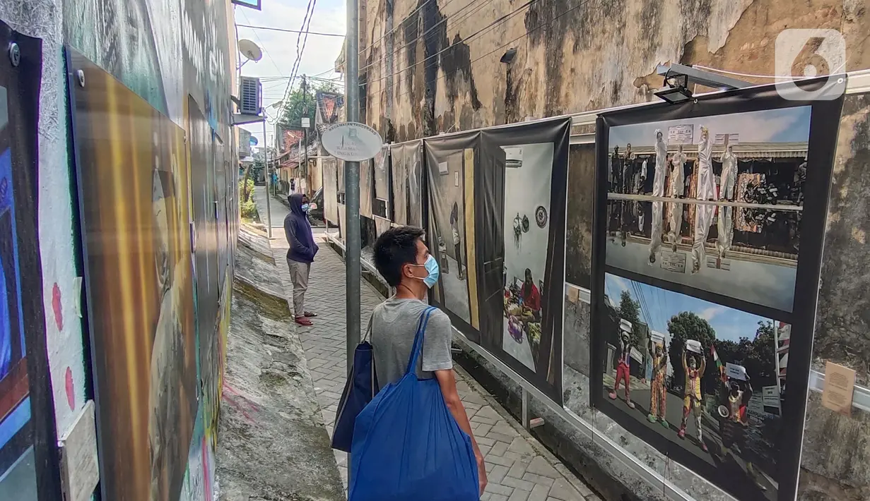 Warga melihat pameran foto jurnalistik karya pewarta foto Indonesia Tangerang di kawasan Pasar Lama, Tangerang, Minggu (30/5/2021).  Pameran foto ini juga mengingatkan masyarakat terus menjaga protokol kesehatan untuk indonesia yang sehat. (Liputan6.com/Angga Yuniar)