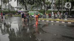 Petugas Penanganan Prasaran dan Sarana Umum (PPSU) membersihkan genangan air saat car free day (CFD) di kawasan Bundaran HI, Jakarta, Minggu (29/12/2019). Pembersihan genangan air dilakukan agar warga yang sedang berolahraga di kawasan tersebut nyaman. (Liputan6.com/Faizal Fanani)