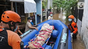 Relawan dan keluarga membawa jenazah warga lansia dengan perahu karet saat banjir di kawasan Cipinang Melayu, Jakarta Timur, Jumat (19/2/2021). Seorang nenek (80) meninggal di kediamannya, di lokasi banjir, di RW 04, kawasan tersebut karena sakit dan sudah lanjut usia. (Liputan6.com/Herman Zakharia)