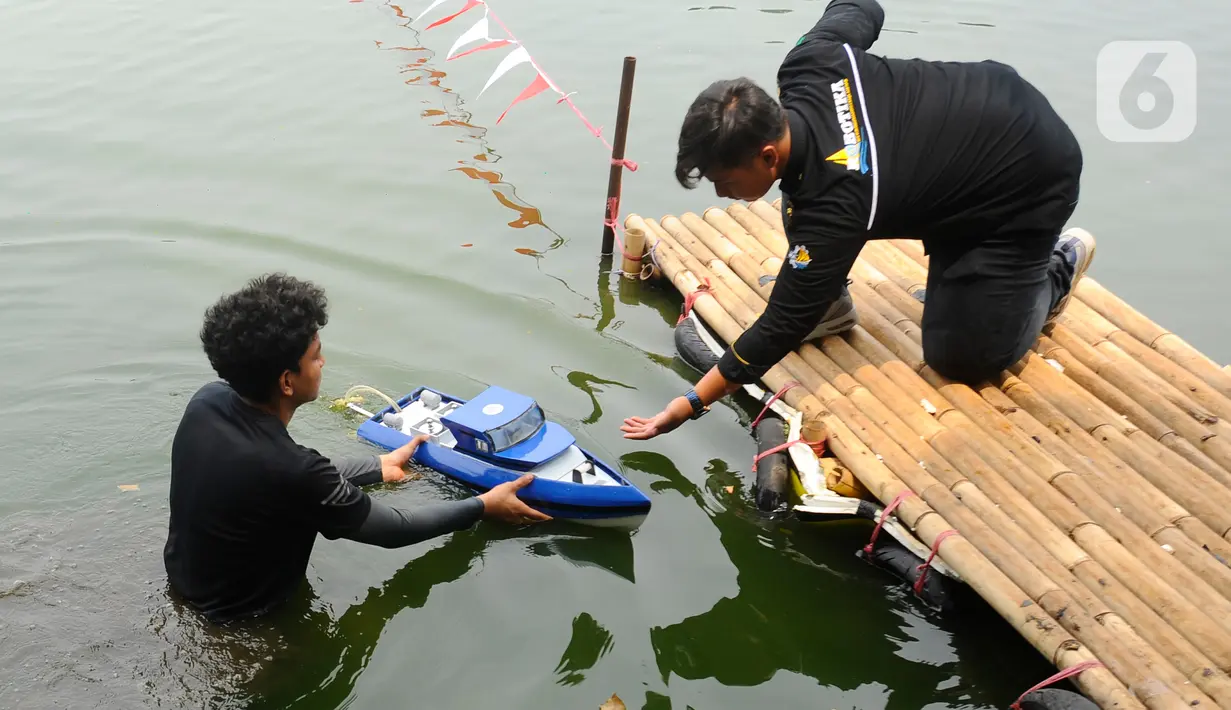 Dua orang mahasiswa menyiapkan kapal cepat tak berawak saat mengikuti Kontes Kapal Cepat Tak Berawak Nasional (KKCTBNdi Danau Kenanga, Kampus UI, Depok, Jawa Barat, Selasa (24/10/2023). (merdeka.com/Arie Basuki)