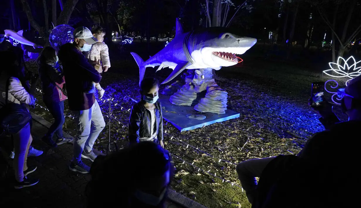 Pengunjung berjalan melewati sosok robot hiu yang menjadi bagian dari dekorasi Natal di Kebun Raya Jose Celestino Mutis, Bogota, Kolombia, 16 Desember 2021. Dari populasi Kolombia yang berjumlah 49.650.000 jiwa, sekitar 71 persen di antaranya beragama Katolik. (AP Photo/Fernando Vergara)