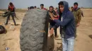 Pemuda Palestina membawa ban untuk dibakar saat menggelar aksi di perbatasan Palestina-Israel di kota Gaza tengah (13/4). Hal tersebut merupakan unjuk rasa ketiga menyusul tewasnya 33 orang Palestina akibat serangan tentara Israel. (AFP/Mohammed Abed)