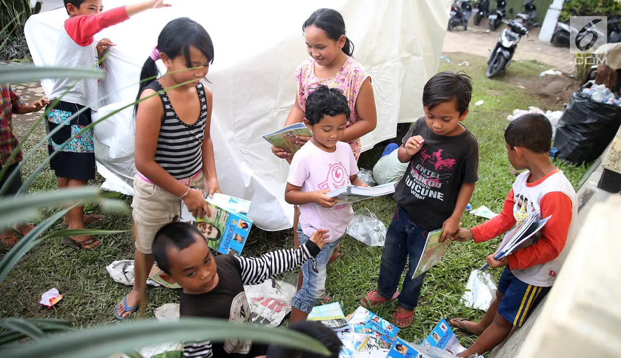 Anak-anak pengungsi Gunung Agung memegang buku di sekitar tenda Posko Pengungsi Rendang, Bali, Sabtu (2/12). Meski dalam keadaan mengungsi anak-anak tersebut tetap ceria saat bermain. (Liputan6.com/Immanuel Antonius)