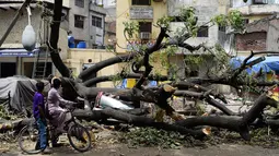 Dua anak melihat mobil yang tertimpa pohon yang tumbang akibat  badai angin kencang di New Delhi, India (16/5). (AFP Photo/Sajjad Hussain)