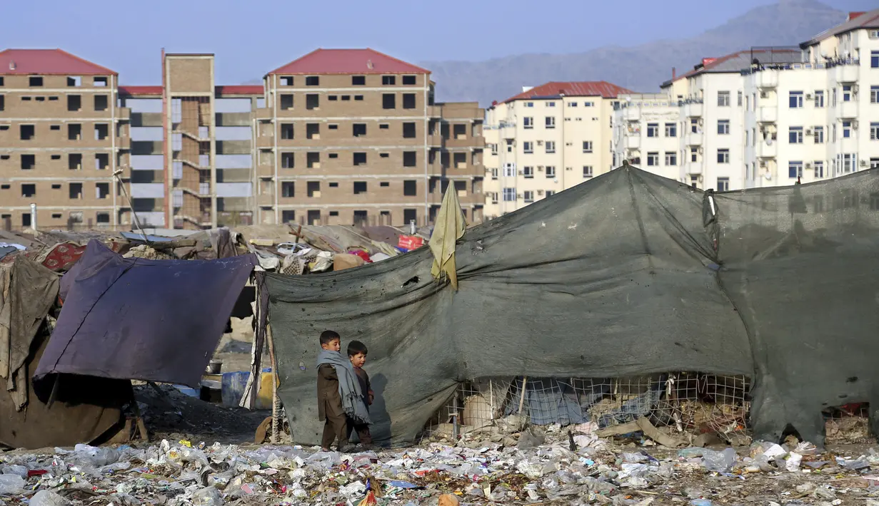 Dua anak laki-laki berjalan di dekat rumah darurat mereka di pinggiran Kabul, Afghanistan (27/11/2019). Puluhan ribu warga Afghanistan yang terlantar secara internal tinggal di kamp-kamp, yang kekurangan fasilitas dasar, di Afghanistan. (AP Photo / Tamana Sarwary)
