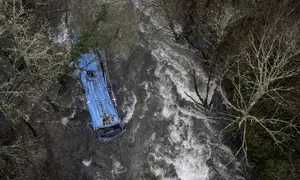 Bangkai bus terlihat di sungai Lerez setelah jatuh saat melintasi jembatan, menewaskan empat orang, di Cerdedo-Cotobade, Spanyol (25/12/2022). Kecelakaan itu terjadi pada 24 Desember malam di dekat Vigo dan perbatasan dengan Portugal. (AFP/Brais Lorenzo)