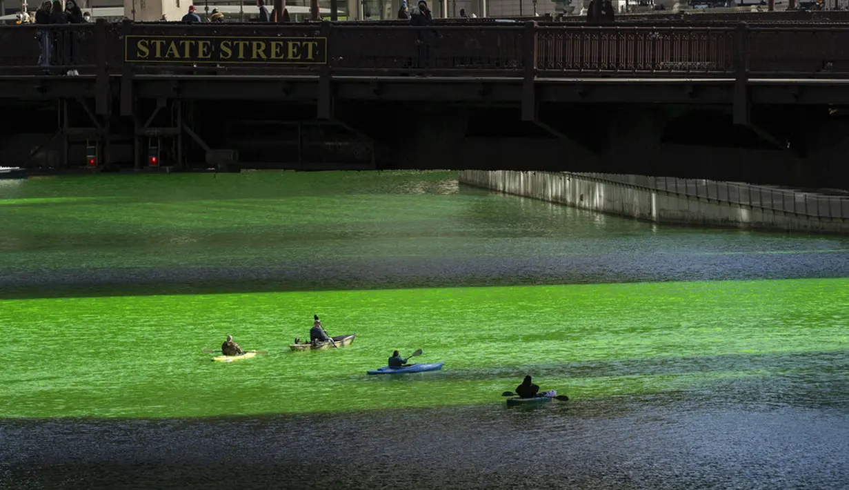 Orang-orang bermain kayak di sepanjang Sungai Chicago yang berwarna hijau jelang Hari Santo Patrick di Chicago, Amerika Serikat, Sabtu (13/3/2021). Kegiatan mewarnai Sungai Chicago dalam rangka memperingati Hari Santo Patrick sudah berlangsung selama 40 tahun. (Pat Nabong/Chicago Sun-Times via AP)