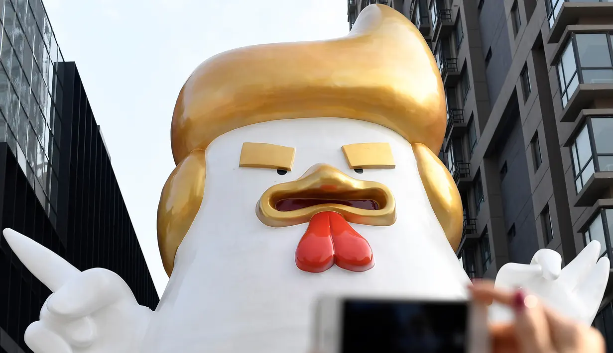Patung ayam berukuran super besar dipajang di pusat perbelanjaan Tiongkok berhasil menyedot perhatian pengunjung, Sabtu (24/12). Pasalnya, patung ayam itu sangat mirip dengan presiden terpilih Amerika Serikat Donald Trump. (AFP PHOTO / STR)