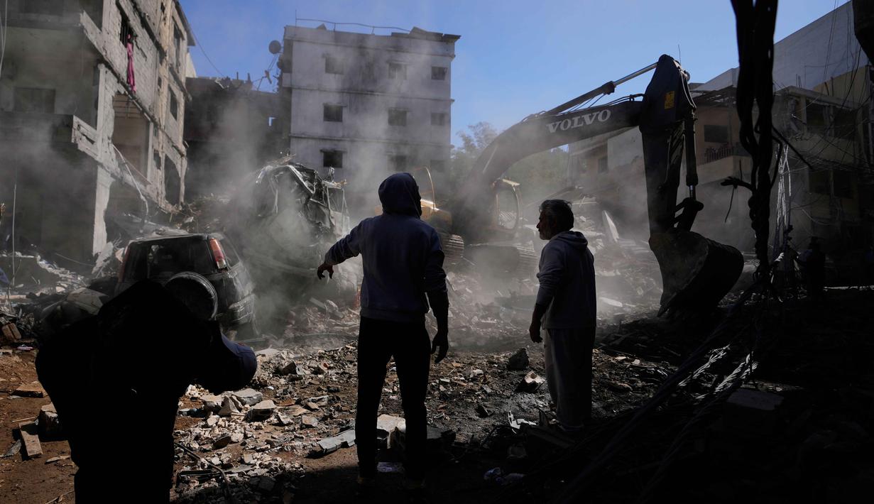 Serangan udara Israel terus menyasar wilayah Lebanon selatan dan pinggiran selatan Beirut, termasuk Jnah. Tampak dalam foto, orang-orang berkumpul saat sebuah ekskavator membersihkan puing-puing di lokasi serangan Israel pada Minggu 5 April 2026 terhadap sebuah bangunan di lingkungan Jnah, Beirut, Lebanon, Senin 6 April 2026. (AP Photo/Hassan Ammar)
