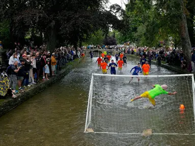 Pemain sepak bola Bourton Rovers berebut bola dalam pertandingan sepak bola tradisional tahunan River Windrush di Desa Cotswolds, Bourton-on-the-Water, Inggris, Senin (28/8/2023). (AP Photo/Frank Augstein)