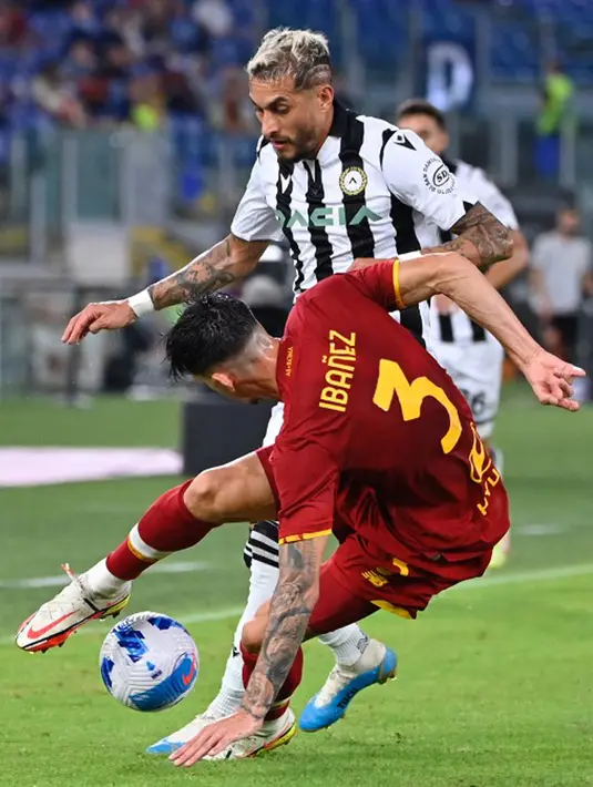 Pemain Udinese Roberto Pereyra (kiri) berebut bola dengan pemain AS Roma Roger Ibanez pada pertandingan Serie A Liga Italia di Olympic Stadium, Roma, Italia, 23 September 2021. AS Roma menang 1-0. (Alberto PIZZOLI/AFP)