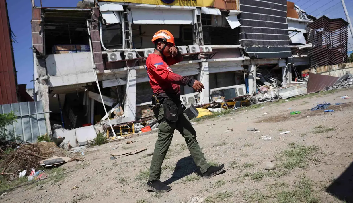 Seorang penyelamat berjalan melewati bangunan yang rusak akibat gempa bumi di General Santos, Filipina, Selasa 9 Juni 2026. (AP Photo/Basilio Sepe)