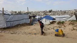 Dalam tugasnya, NCAG akan bertanggung jawab kepada Dewan Perdamaian Gaza. Tampak dalam foto, seorang anak laki-laki Palestina yang mengungsi dan hidup di antara reruntuhan rumah dan bangunan yang hancur akibat serangan militer Israel selama lebih dari dua tahun di wilayah Gaza, menyeret kontainer berisi air di kamp pengungsi Jabalia, di bagian utara Jalur Gaza pada Sabtu 17 Januari 2026. (Omar AL-QATTAA/AFP)