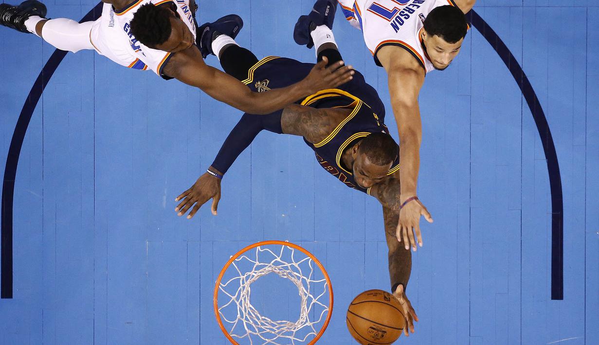 Pebasket Cleveland Cavaliers, LeBron James, menghindari block pebasket Oklahoma City Thunder, Jerami Grant dan Andre Roberson. Ini merupakan kekalahan ke-16 bagi Cavs pada musim ini. (EPA/Larry W. Smith)
