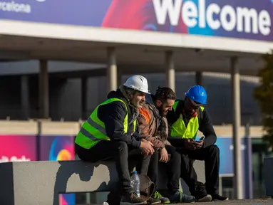 Para pekerja Mobile World Congress (MWC) 2020 duduk di luar lokasi pameran di Barcelona, Spanyol, Kamis (13/2/2020). Penyelenggara MWC 2020, GSMA, batal menggelar pameran telekomunikasi terbesar di dunia tersebut karena ancaman virus corona. (AP Photo/Emilio Morenatti)
