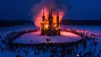 Sejumlah warga menonton bangunan bergaya gothik karya seniman Nikolay Polissky yang dibakar saat perayaan Shrovetide di wilayah Kaluga, Rusia (17/2). Perayaan ini menandai berakhirnya musim dingin yang dirayakan sejak masa pagan. (AFP/Dmitry Serebryakov)