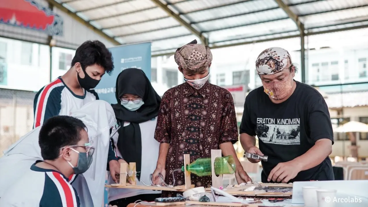 Seniman Sinau membantu siswa merakit material untuk instalasi saringan air.